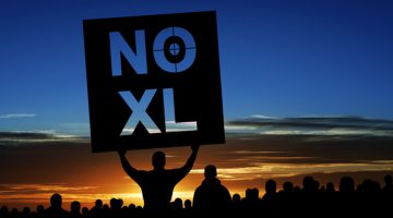 Keystone pipeline protestors in silhouette with man holding "NO XL" sign